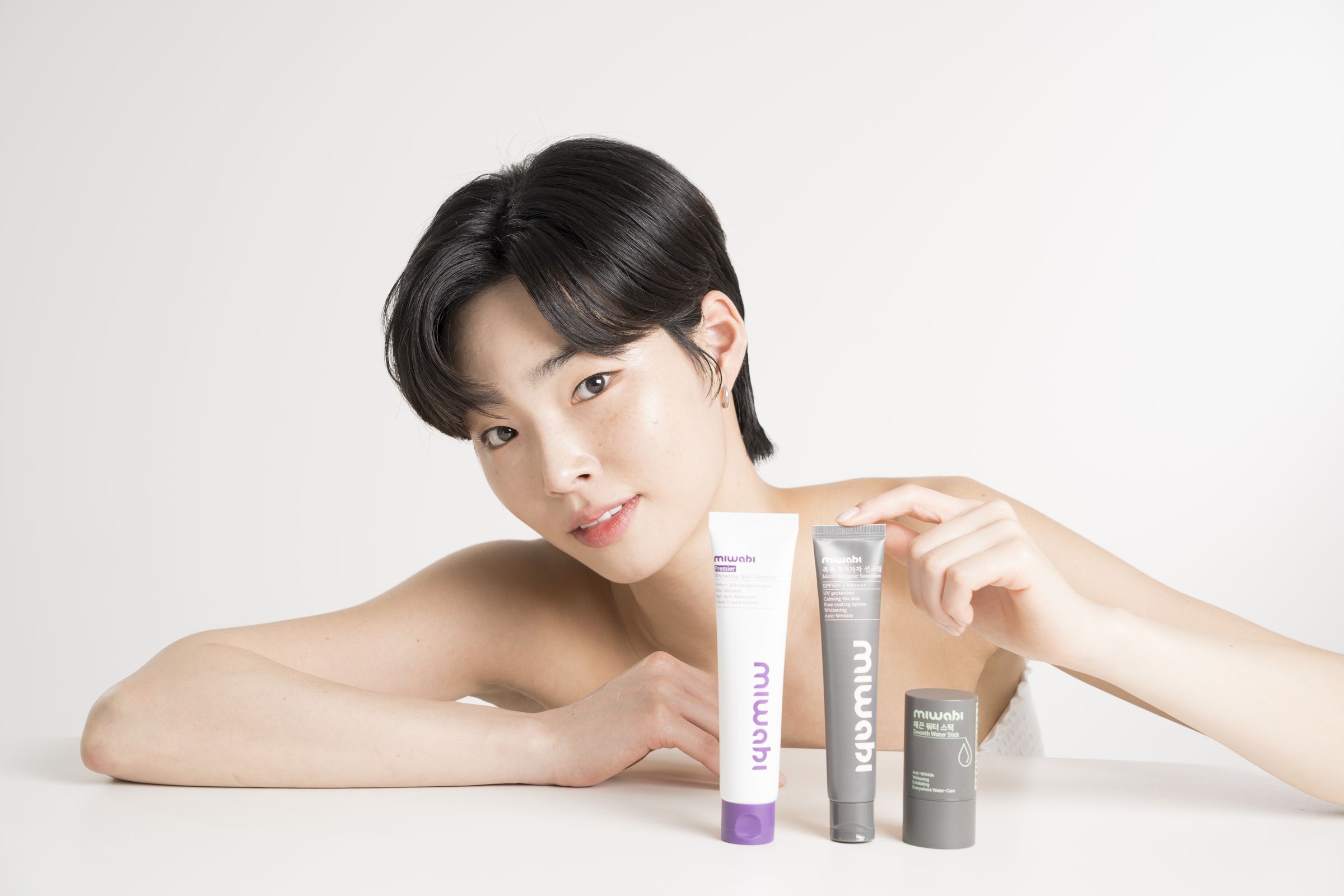 미와비 스팟 코렉터, 선크림, 워터 스틱을 앞에 두고 미소 짓는 모델