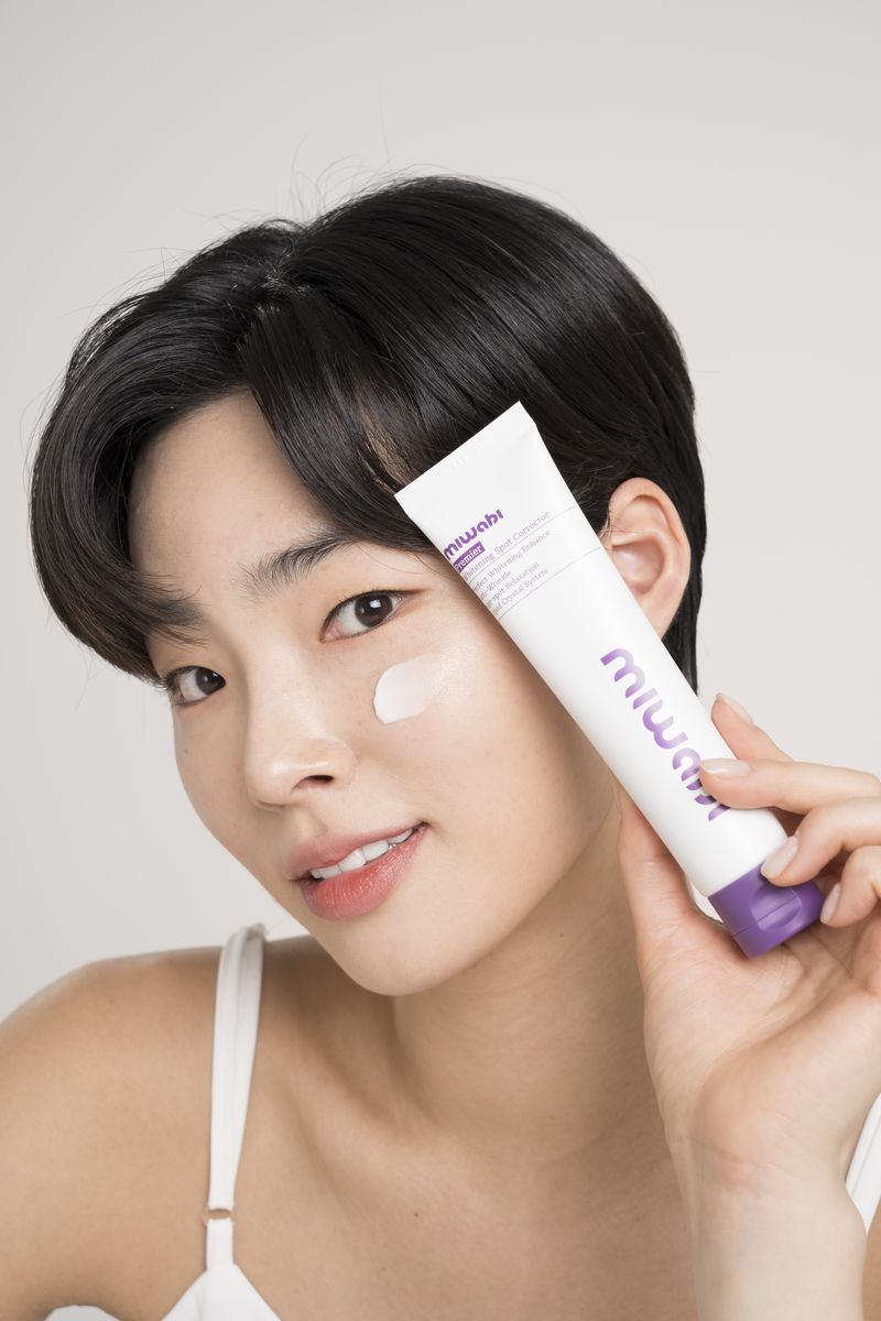 볼에 크림을 바르고 스팟 코렉터를 든 모델
